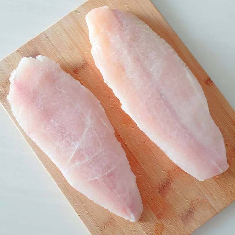 Dua lembar fillet dori putih di atas talenan